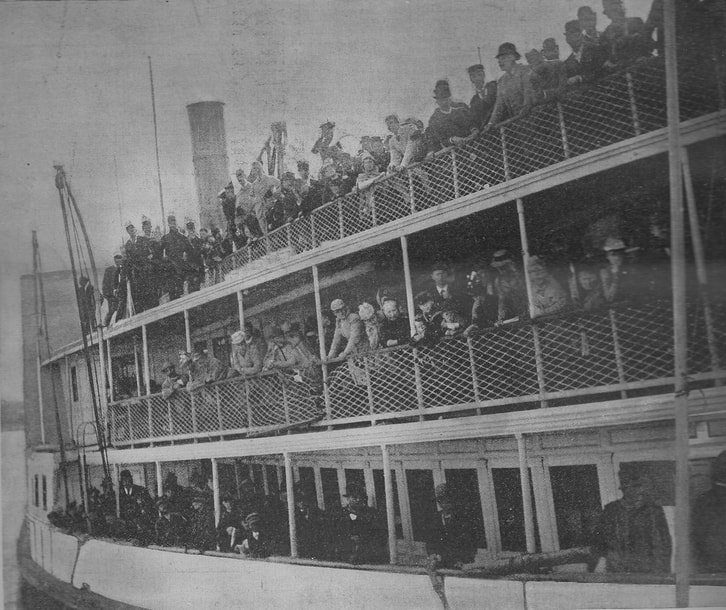 Black and white photograph of the side of a crowded ship at dock, showing three tiers of people
