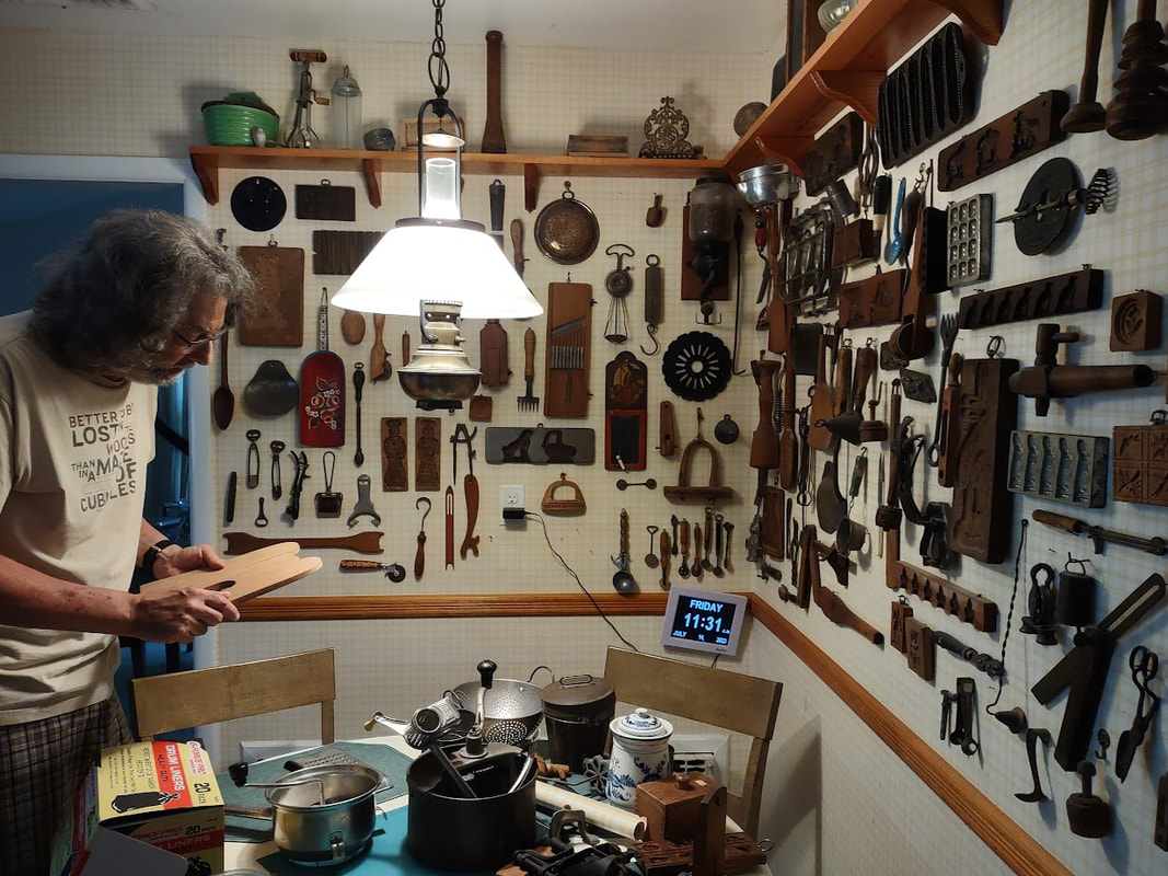 The corner walls of a kitchen are mounted with at least 100 vintage and antique cooking and baking tools and gadgets